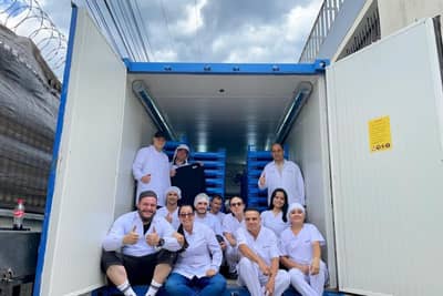 People gathered at an open blue container used for black soldier fly production.