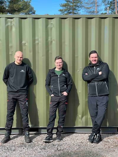 Three members of the Manna Insect team standing in front of a green container.