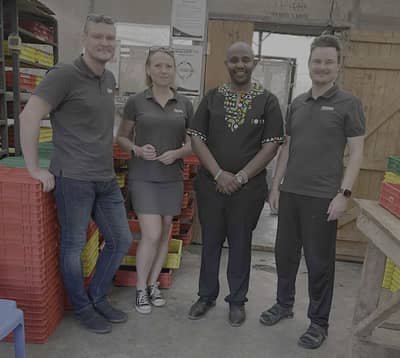 People standing among stacked red and yellow crates in a production facility.